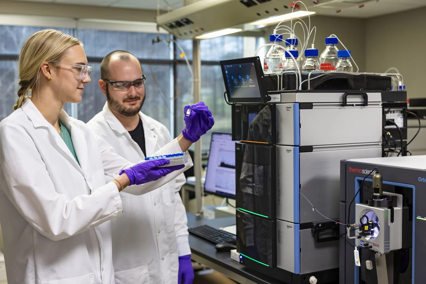 Megan Elliott and Steven Tavis work with mass spectrometry instrumentation at ORNL.
