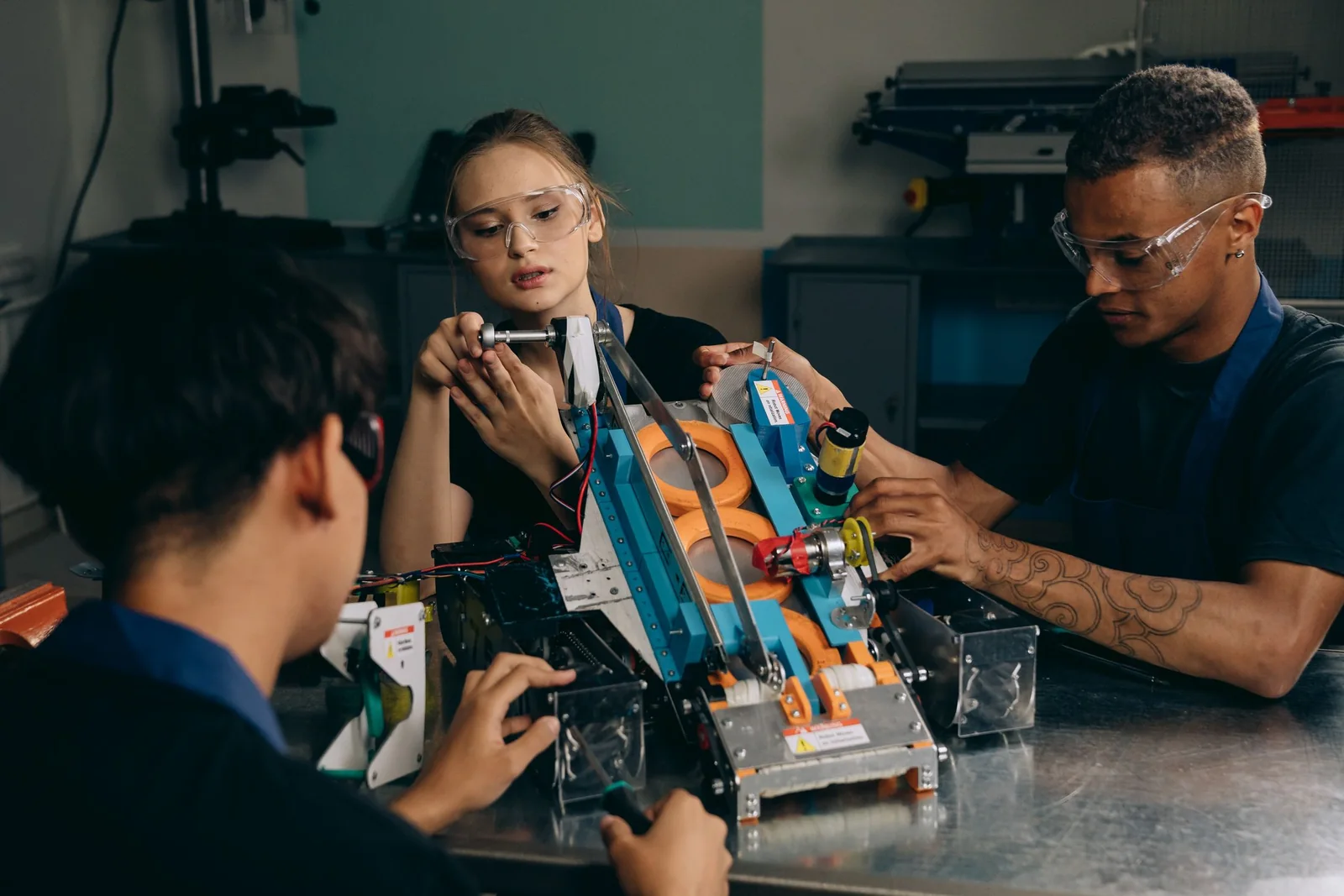 Engineers collaborate on assembling a robotic prototype at a workshop bench.