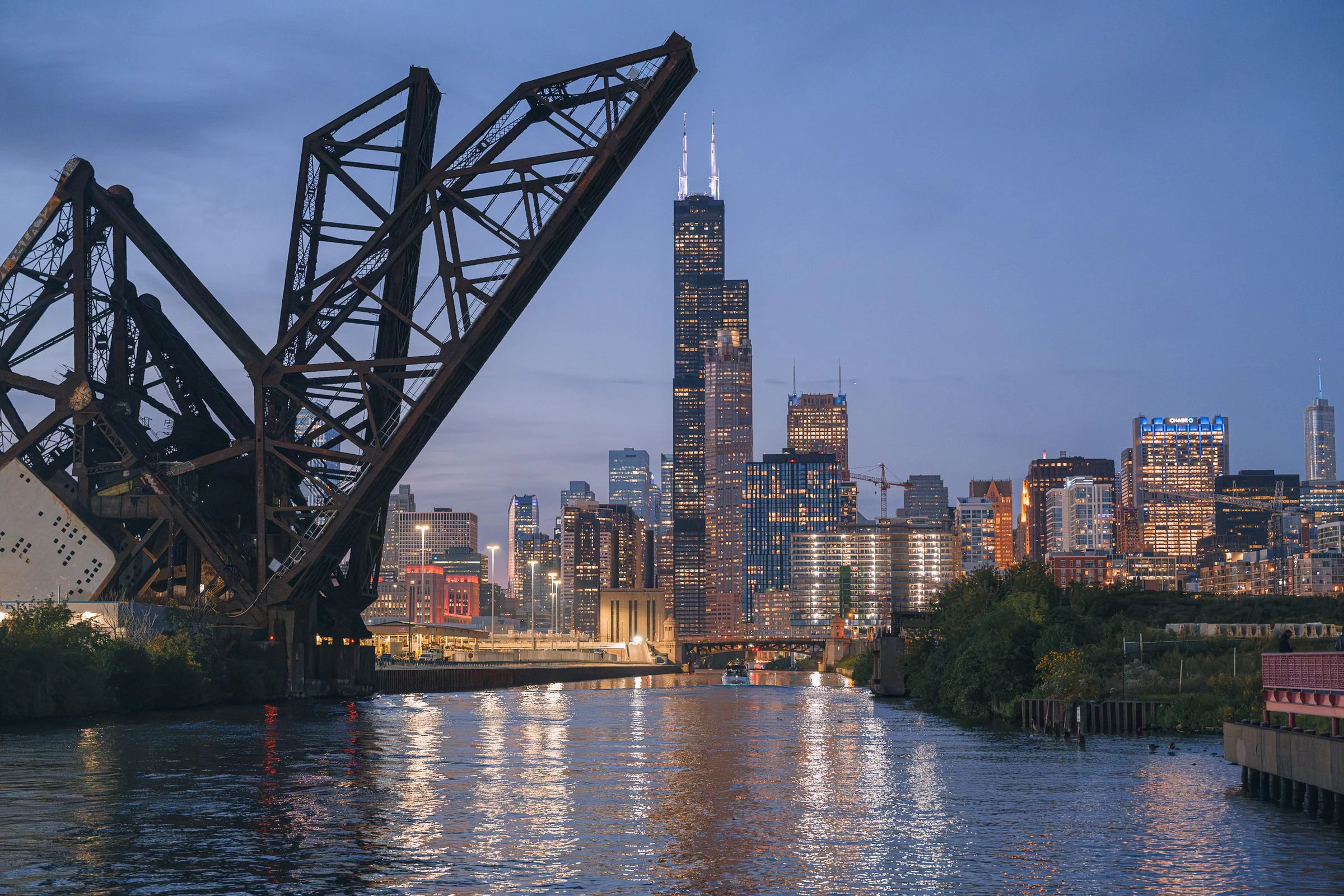 Chicago skyline, river, and raised industrial railway bridge at twilight, photographed September 28, 2026.