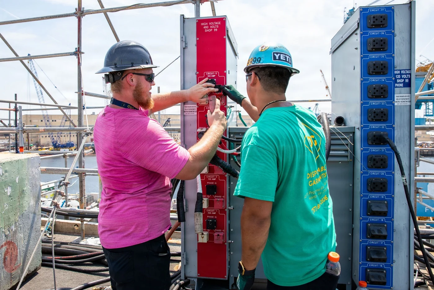 Electrician Donald Davis and pipefitter Jamison Walker connect power cables at Norfolk Naval Shipyard in Portsmouth, Virginia, August 2026.