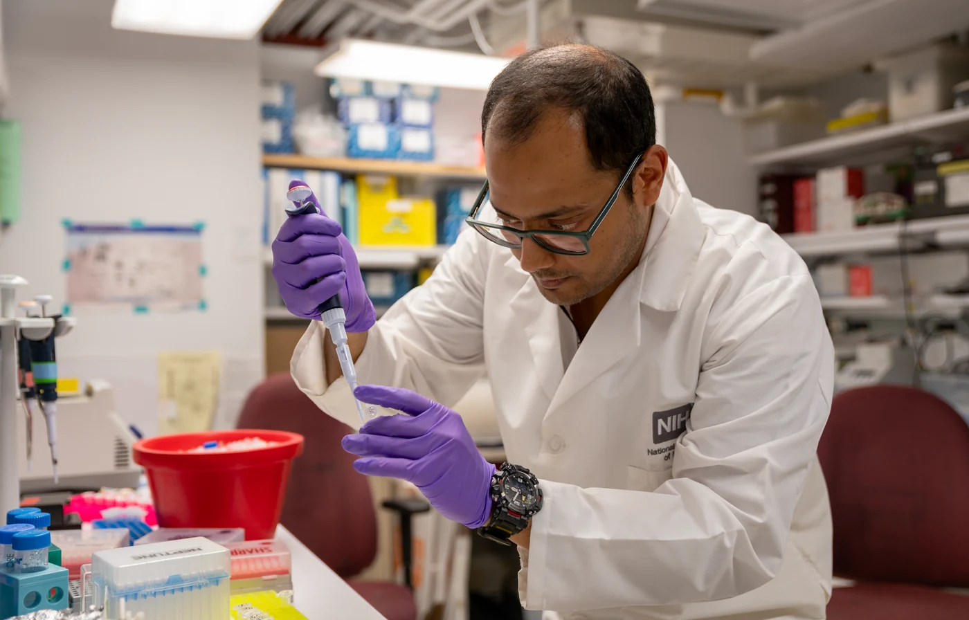 An NIH researcher handles a sample at a laboratory bench.